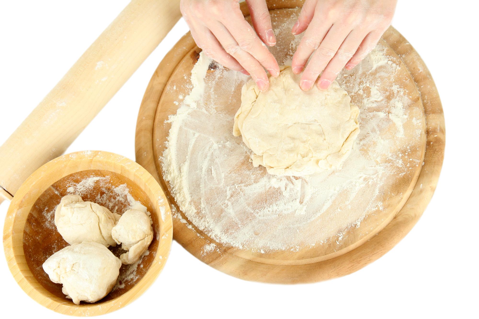 hands shaping dumplings on floured surface