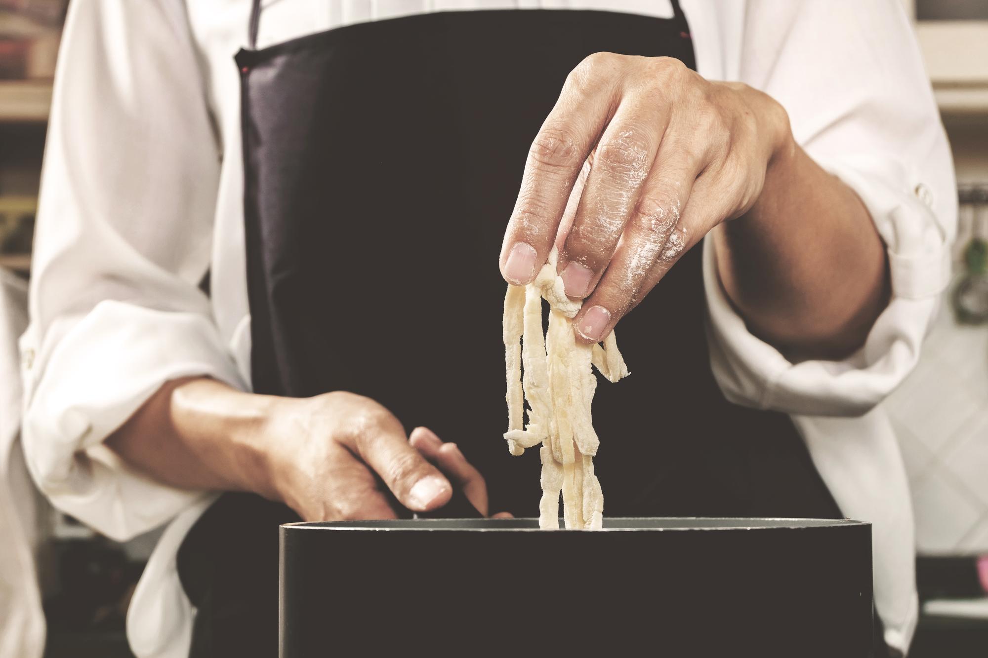 hands folding fresh pasta in warm studio light